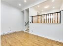 Unfurnished living room featuring baseboard heating, light wood finished floors, crown molding, stairs, and recessed lighting