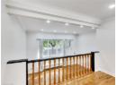 Hallway with wood finished floors, ornamental molding, recessed lighting, and an upstairs landing