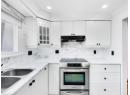 Kitchen featuring stainless steel range with electric cooktop, white cabinetry, and tasteful backsplash