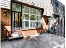 Property entrance featuring brick siding, mansard roof, and a patio area