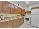 Kitchen featuring white appliances, tasteful backsplash, brown cabinetry, and light tile patterned floors