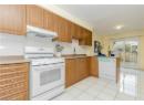 Kitchen with white appliances, light tile patterned floors, a peninsula, backsplash, and under cabinet range hood