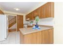 Kitchen with white appliances, a peninsula, light tile patterned floors, decorative backsplash, and light countertops