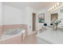 Bathroom featuring light tile patterned floors, vanity, a garden tub, and tiled shower