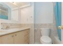 Full bath with vanity, tile walls, light tile patterned flooring, shower / bathtub combination with curtain, and wainscoting