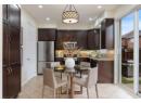 Kitchen with stainless steel appliances, dark brown cabinetry, backsplash, light tile patterned floors, and pendant lighting