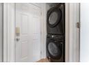 Laundry room with stacked washer and clothes dryer and light tile patterned floors